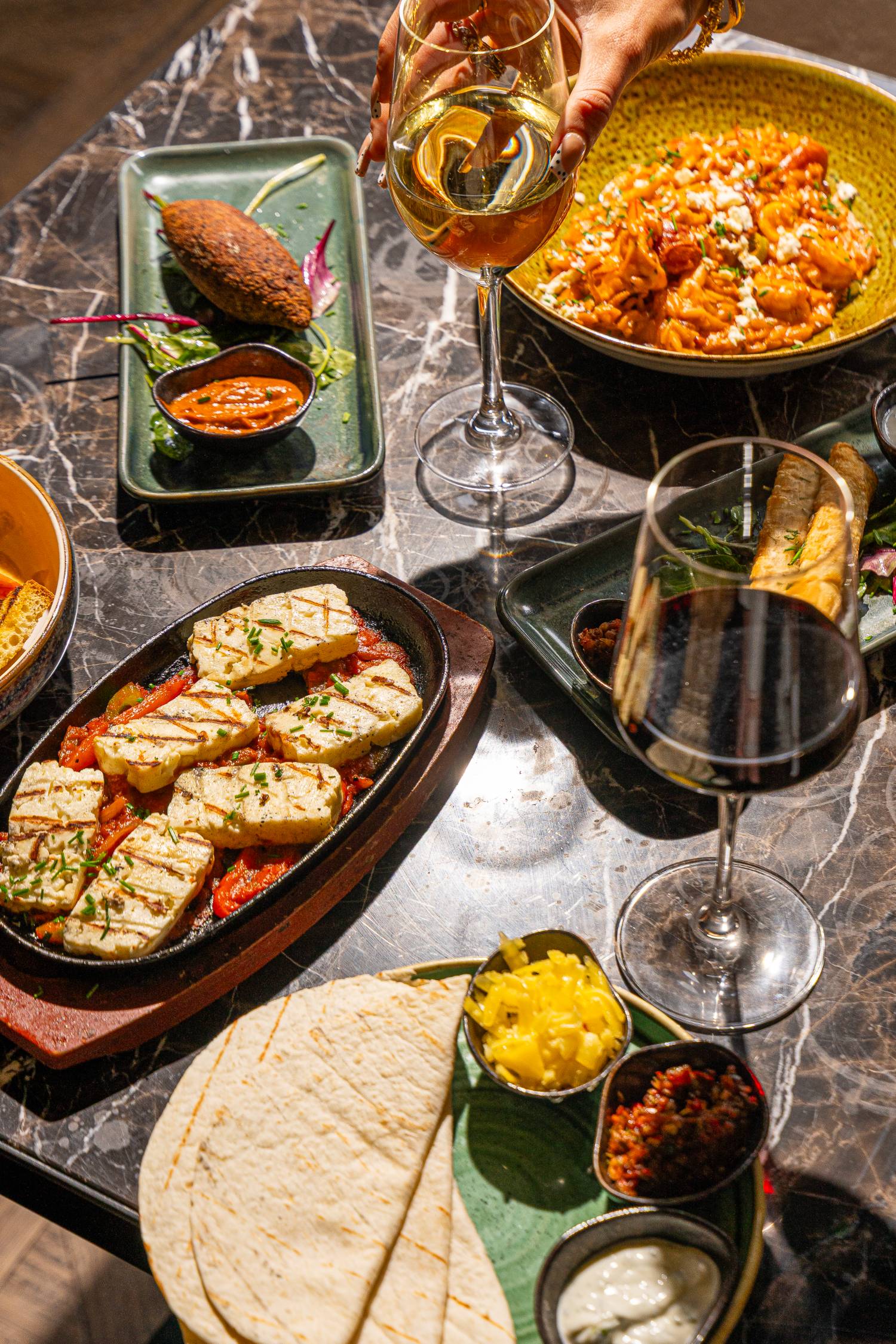 Halloumi, orzotto and mezze across a marble table