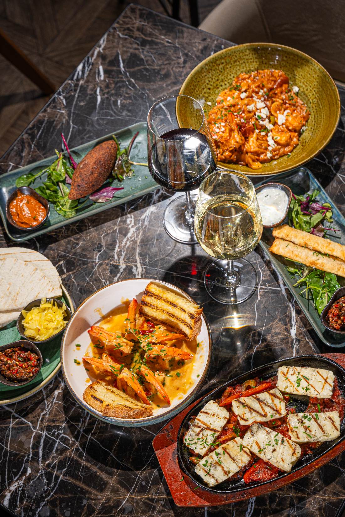 A marble table spread with Mediterranean tapas plates